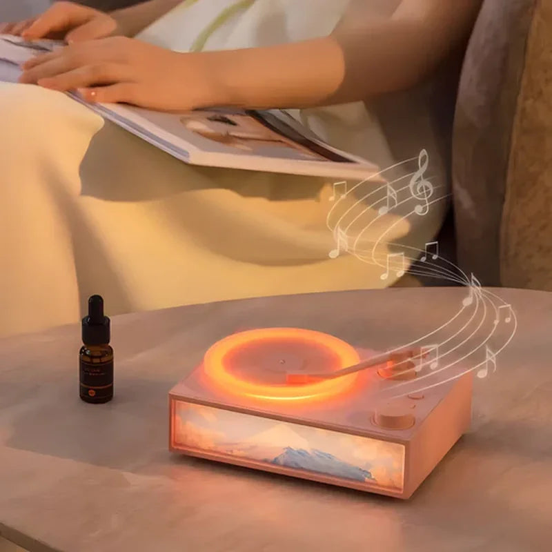 gramofon sa bluetooth zvučnikom i difuzerom pored knjige na stočiću
