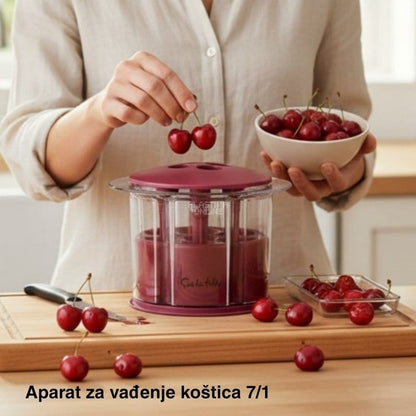 žena ubacuje trešnju u uređaj dok drži činiju punu trešanja u kuhinji