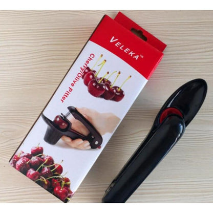 pakovanje Veleka cherry olive pitter pored crnog alata na drvenoj podlozi