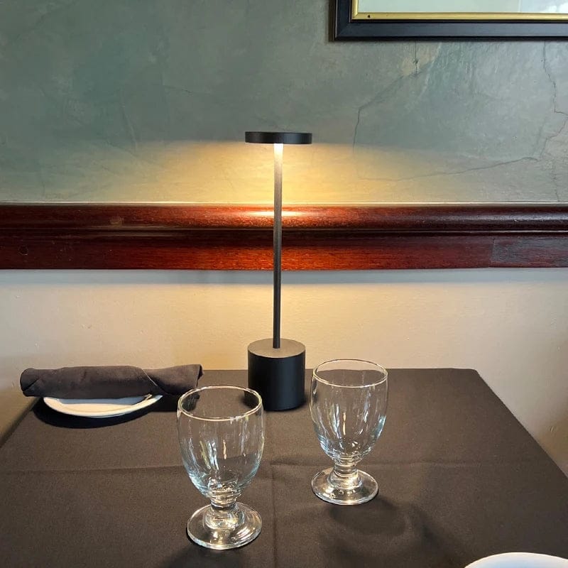 bežična led stona lampa za restorane crna na stolu restorana sa čašama i escajgom