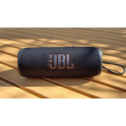 vodootporni bluetooth zvučnik IP67 marke JBL sa tkaninom na drvenom stolu napolju