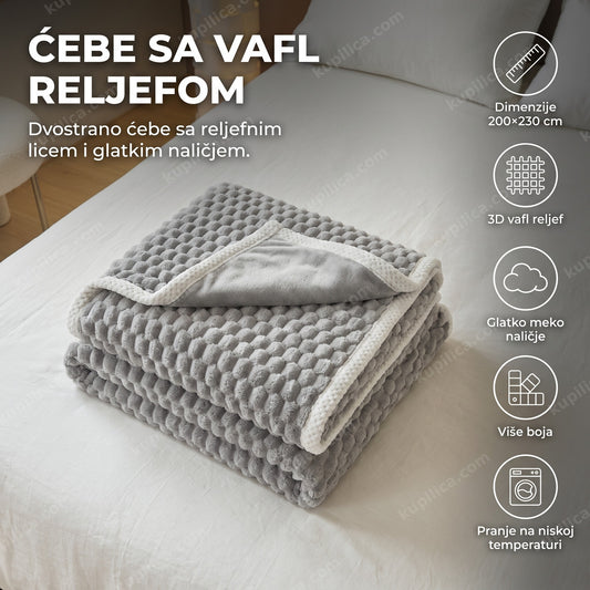 sivo mekano ćebe sa vafl reljefom presavijeno u podnožju kreveta