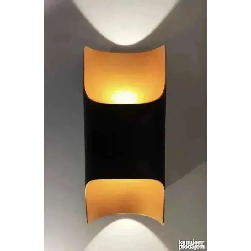 crna cilindrična lampa sa zakrivljenim pozlaćenim segmentima izbliza