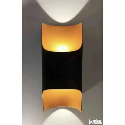 crna cilindrična lampa sa zakrivljenim pozlaćenim segmentima izbliza
