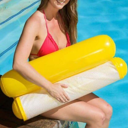 devojka u bikiniju sedi na ivici bazena i drži smotanu žutu plutajuću ležaljku