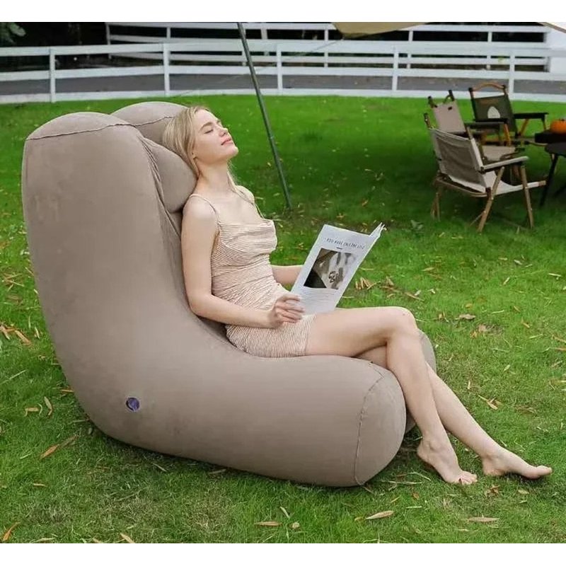 sofa na naduvavanje u dvorištu, žena naslonjena čita knjigu na travi