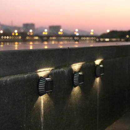 tri solarne zidne lampe na betonskom zidu uz reku u sumrak, svetlo gore i dole