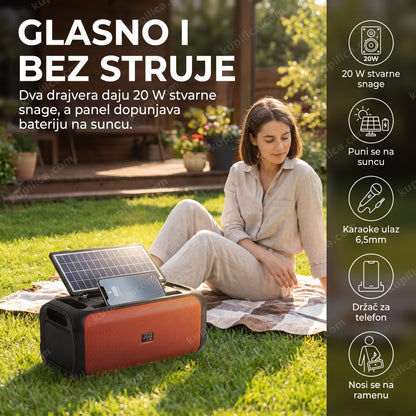 solarni bluetooth zvučnik jz-002 20w — žena sedi na ćebetu u dvorištu pored zvučnika sa solarnim panelom, karaoke ulaz, držač za telefon