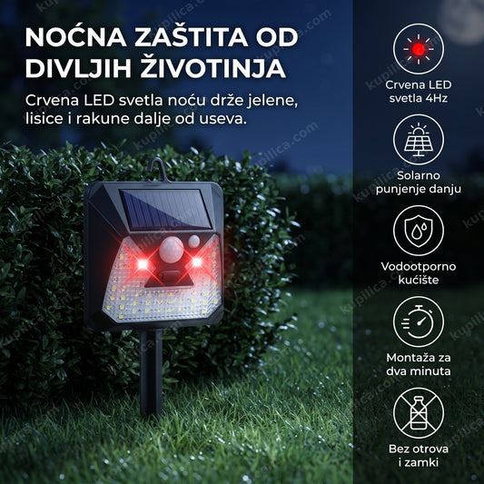 solarni rasterivač životinja sa upaljenim crvenim LED svetlima na travnjaku uz živu ogradu noću