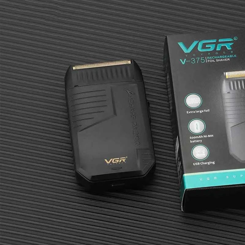 ruka drži brijač VGR V-375 pored kutije i USB kabla na plavoj podlozi