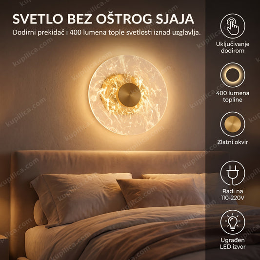 Zidna lampa zlatna sa akrilnim diskom iznad uzglavlja kreveta u spavaćoj sobi